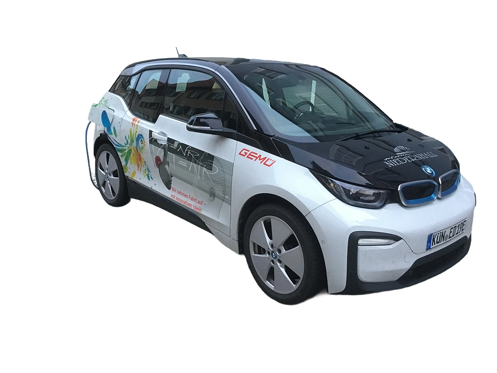 BMW i3 Elektroauto mit farbigem Design und Firmenlogo, seitlich beschriftet mit Werbebotschaft für nachhaltige Mobilität.