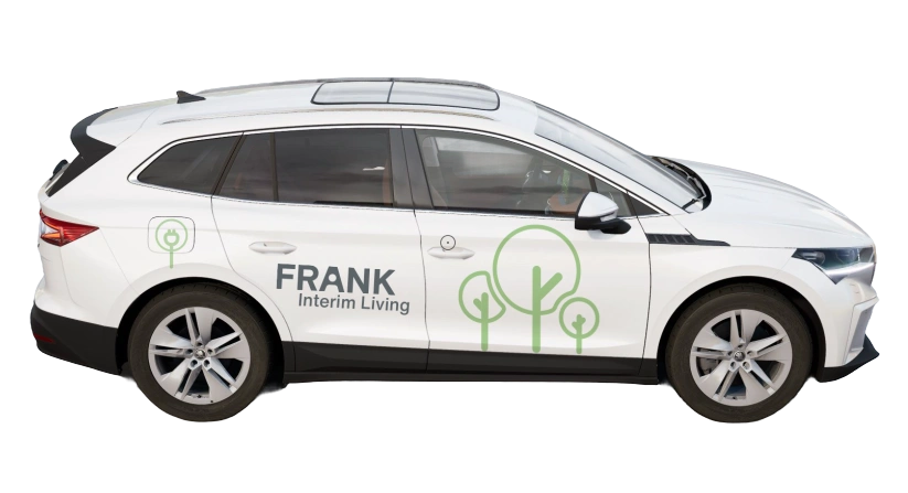 Weißes Fahrzeug mit der Aufschrift ‚FRANK Interim Living‘ und grünen Baumgrafiken auf der Seite.