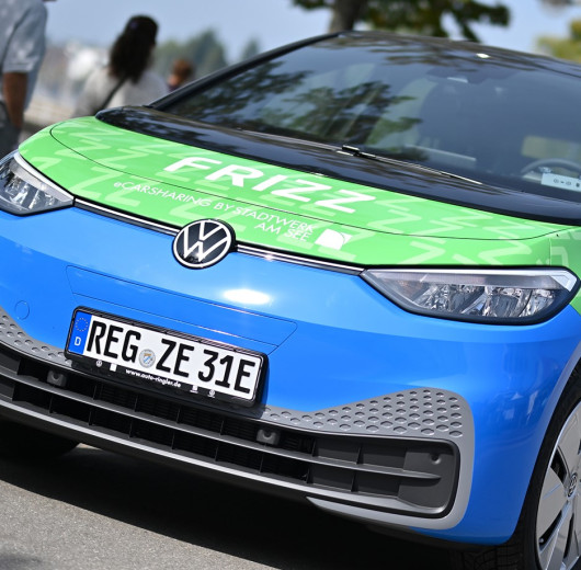 Blaues Elektroauto VW ID.3 mit grünem FRIZZ-Logo und Slogan auf Motorhaube als Fahrzeug für nachhaltiges Carsharing-Angebot