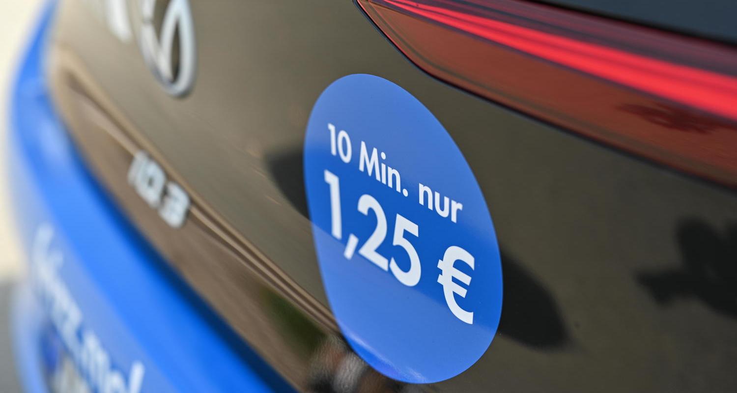 Preisaufkleber auf Heckseite eines Elektroautos mit Hinweis „10 Min. nur 1,25 €“ als Info zur Carsharing-Tarifstruktur ?>