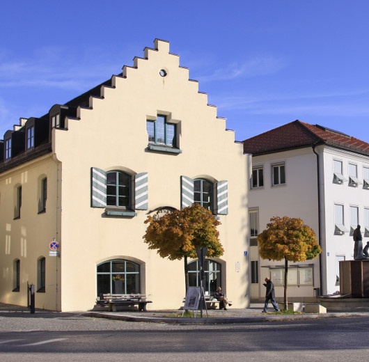 Historisches Gebäude mit Treppengiebel und angrenzendem Rathausplatz mit Fahnen und Brunnen.
