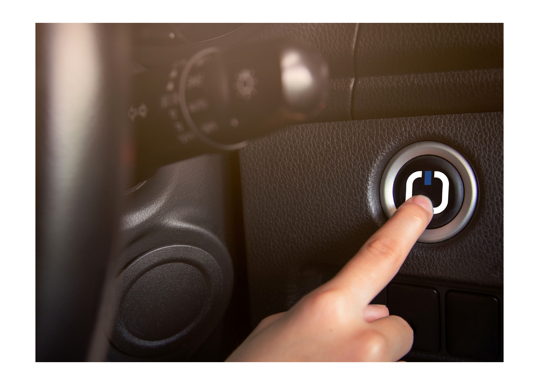 Finger drückt den Startknopf im Auto auf einer schwarzen Armaturenfläche. ?>